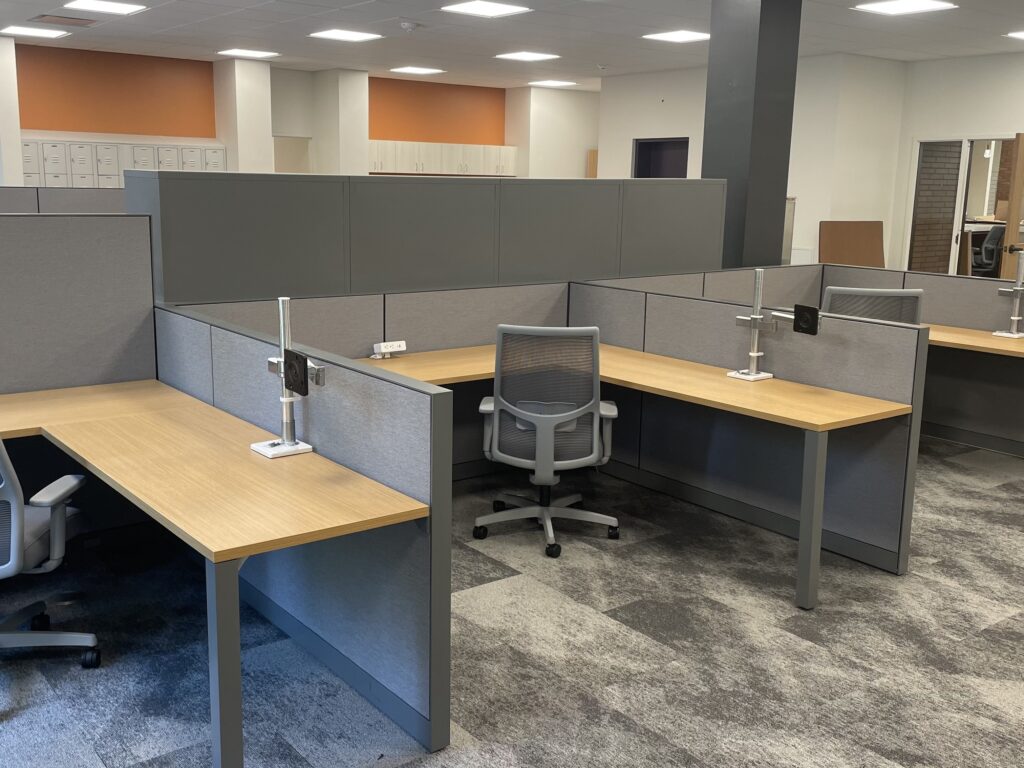 Commercial cubicle installation featuring gray partitions, wood desks, and ergonomic chairs in a modern corporate office