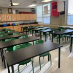 children's classroom with rows of black tables and green chairs