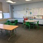 white circle tables and green chairs in school classroom