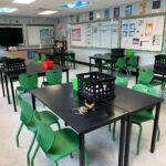 school classroom with black tables and green chairs