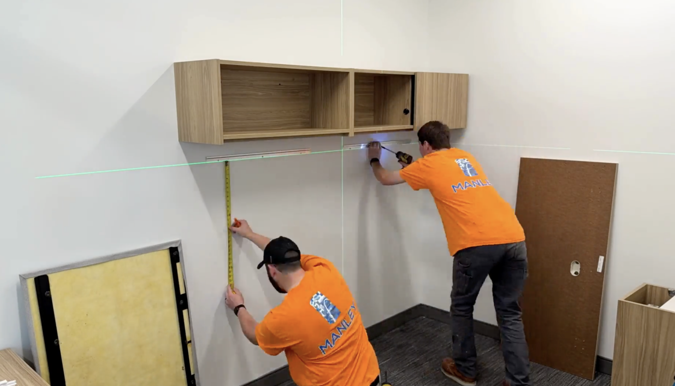 Two installers precisely measuring and leveling office furniture